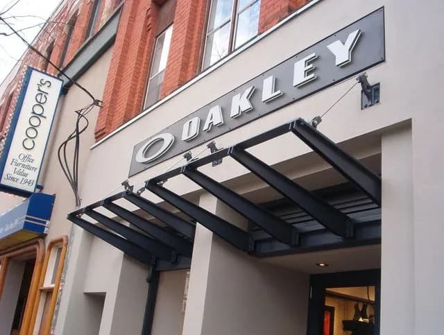 Black steel canopy with glass panels above a storefront entrance on a commercial street