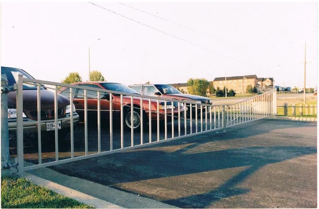 Long white painted picket fence running along the edge of a parking area