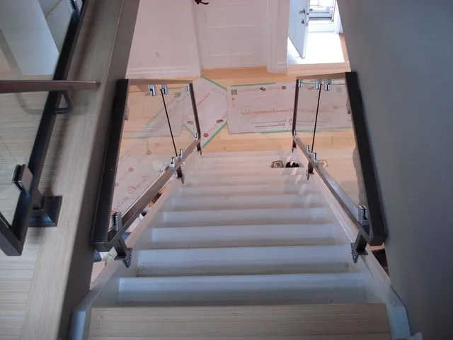 Stainless steel posts with glass panels along a staircase seen from the top landing