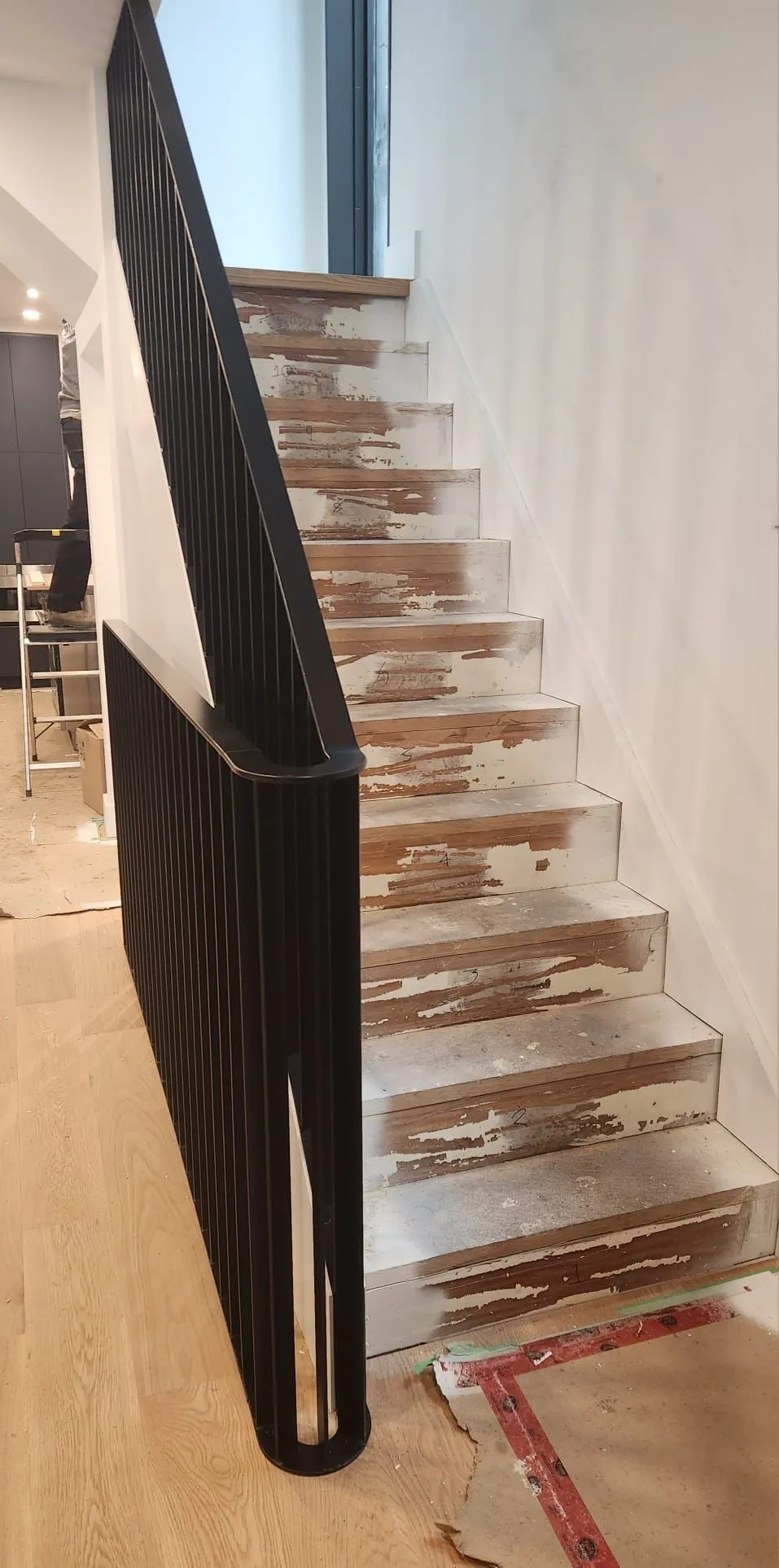 Black metal stair railing with a shaped profile running beside light wood stair treads