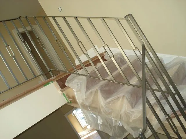 Stainless steel guard with vertical bars around an open stairwell during finishing work