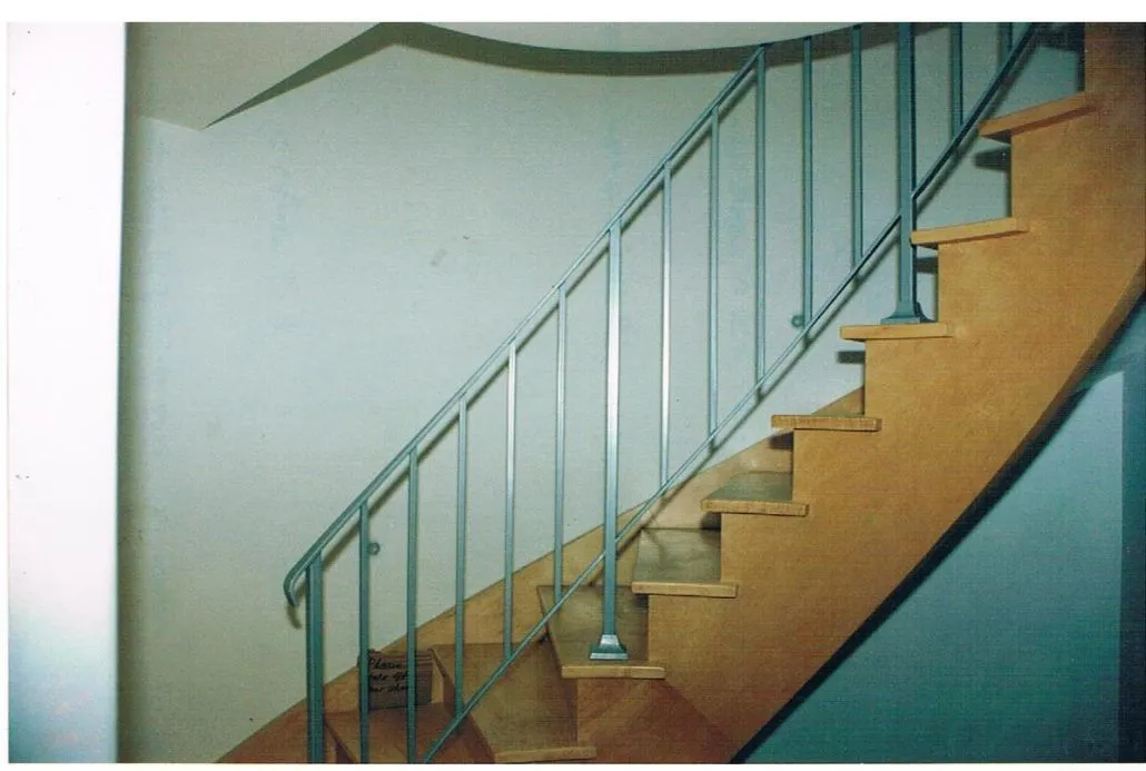 Stair railing with glass panels and a metal cap rail beside a curved wood staircase