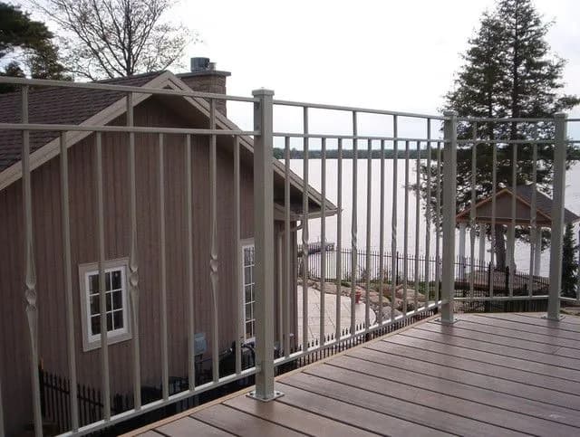 White picket railing with square posts around a raised wood deck beside a gabled roof