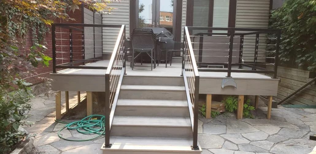 Horizontal cable railings on wide deck stairs leading down to a flagstone patio