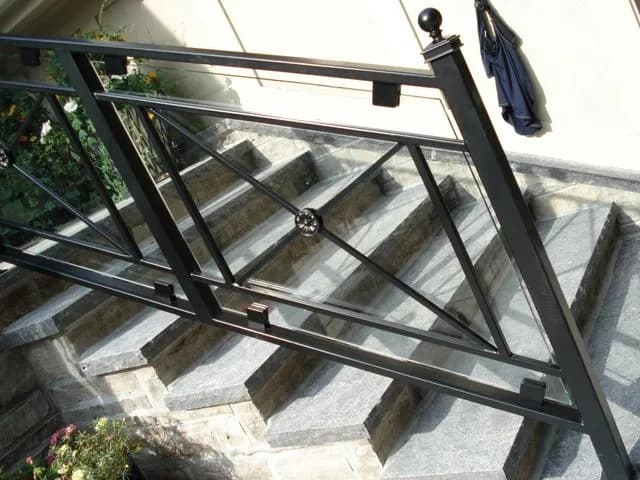 Black metal railing with a ring detail in the panel running beside wide stone steps