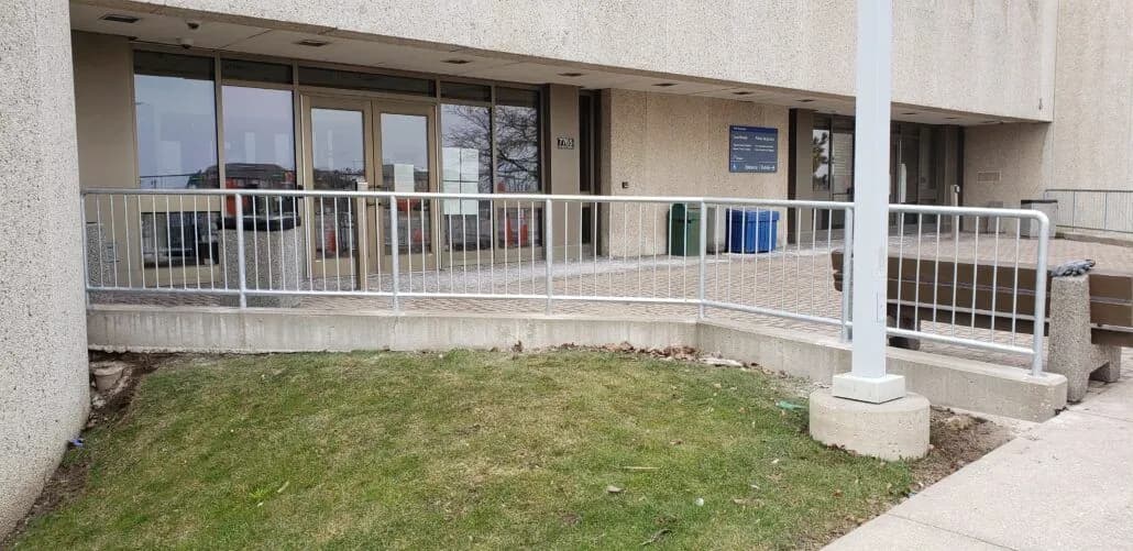 White painted picket railing following a ramp and landing at a building entrance