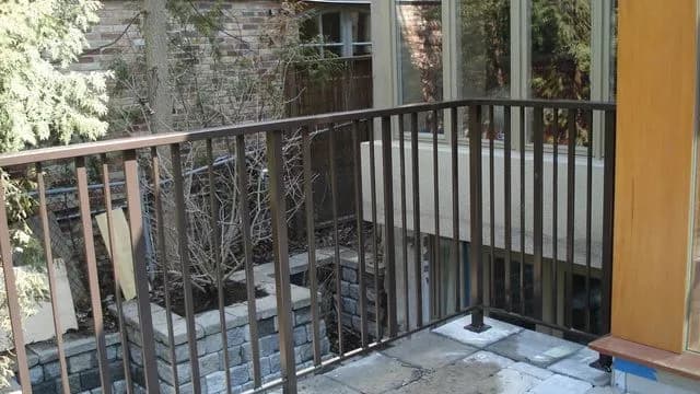 Black metal railing with vertical pickets around a raised landing at a rear entrance