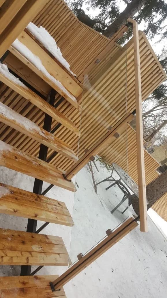 Black steel posts and a handrail under a wood deck frame during construction in winter