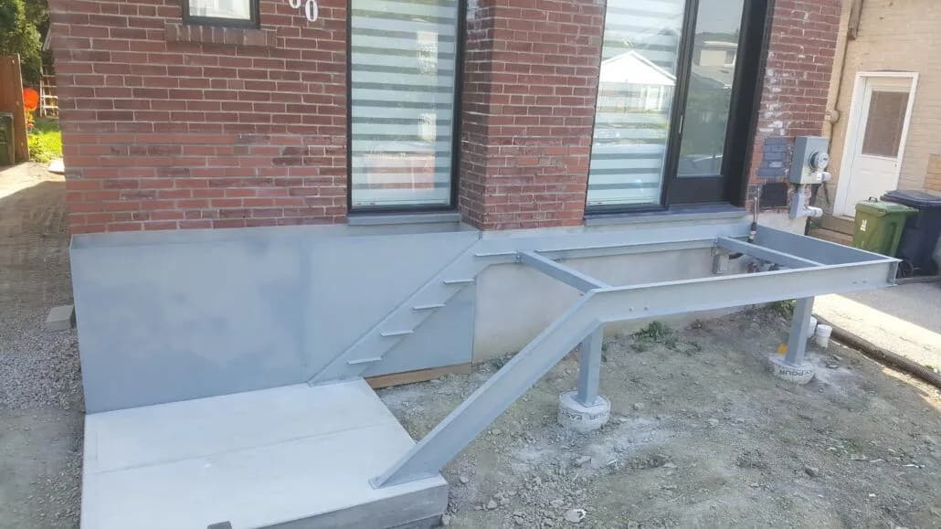 Primed grey steel stair stringer and landing frame outside a building before the treads are fitted