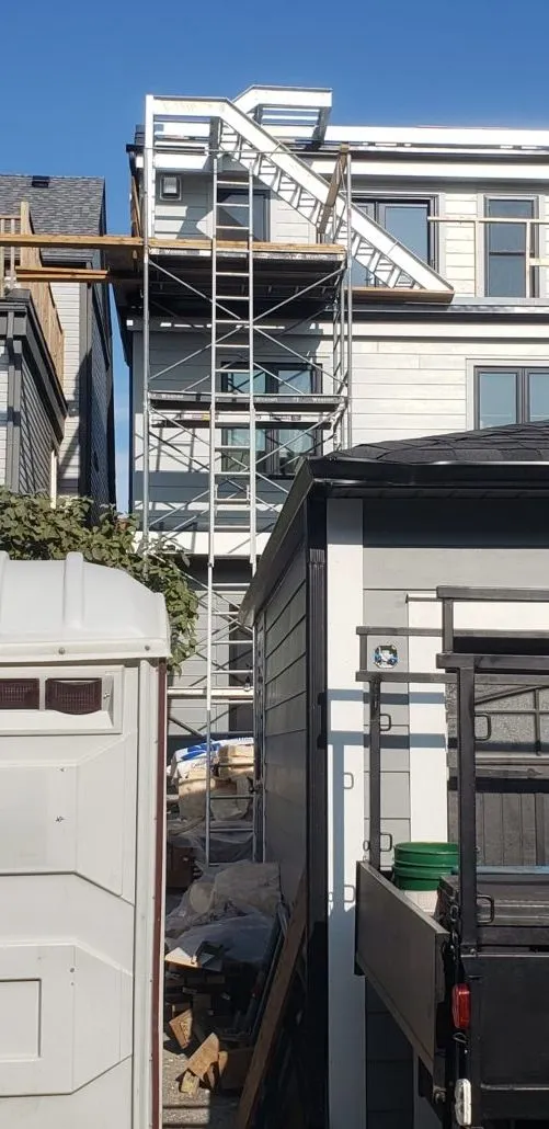 Steel exterior stair and landing behind scaffolding at the back of a house