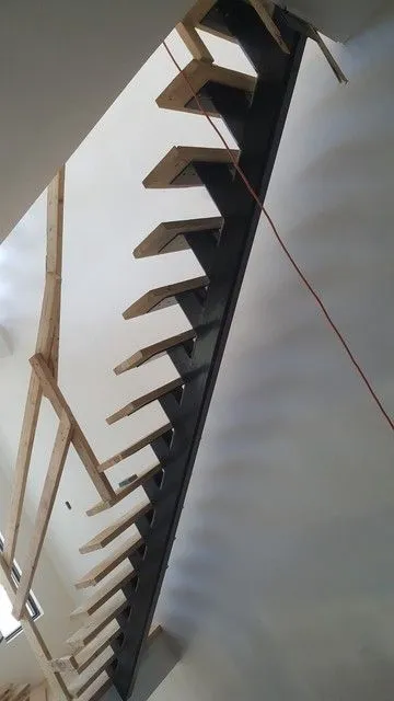 Sawtooth-cut steel stair stringer fixed against a wall before the treads are fitted